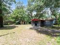 View of the spacious backyard featuring mature trees, storage buildings, and a well-maintained lawn at 20703 Old Trilby Rd, Dade City, FL 33523
