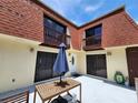 View of the home's exterior with balconies, patio, and table with umbrella at 8114 Oak Trace Way # C, Tampa, FL 33634