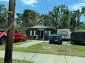 Street view showcasing the home's exterior and front yard with parked vehicles and overgrown grass at 3613 Deleuil Ave, Tampa, FL 33610