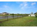 The backyard features a well-maintained lawn, fenced perimeter, and serene pond view at 7163 Talamore Dr, Wesley Chapel, FL 33545