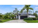 Side view of a one-story home showcasing a well-maintained lawn and lush tropical landscaping at 2421 Valkaria Ave, North Port, FL 34286