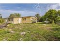 Exterior shot of the yellow home showcasing the spacious backyard and mature trees on a sunny day at 5101 Town N Country Blvd, Tampa, FL 33615