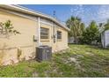 Rear of home with small windows, central air conditioner, and a partially-fenced yard with grass and sandy spots at 5101 Town N Country Blvd, Tampa, FL 33615