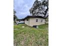 Shows the side of the house with a small grassy area, showcasing the home's simple architecture at 5026 Osprey Ln, New Port Richey, FL 34652