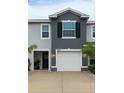 Close up of townhome exterior featuring an attached garage, tidy landscaping, and a covered entryway at 2913 Suncoast Plains Dr, Odessa, FL 33556