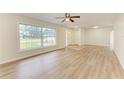 Bright living room featuring light wood floors, ceiling fan, and large window that bring in ample natural light at 221 Vermont E Ave, Bradenton, FL 34208