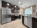 Stylish kitchen with stainless steel appliances, granite countertops, and dark cabinetry overlooking the dining area at 26835 Juniper Bay Dr, Wesley Chapel, FL 33544