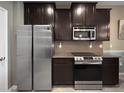 Modern kitchen featuring stainless steel appliances, granite countertops, and dark wood cabinetry at 26835 Juniper Bay Dr, Wesley Chapel, FL 33544