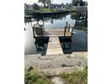 Wooden dock with a small seating area extends into the calm canal waters at 13725 Plumosa Ave, Hudson, FL 34667