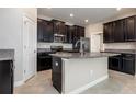 Modern kitchen featuring dark cabinets, granite countertops, stainless steel appliances, and a center island with a sink at 13209 Haystack Ct, Riverview, FL 33579