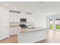 Bright kitchen with white cabinets, island, and sliding glass doors to the backyard at 1732 Brekey Way, Zephyrhills, FL 33541