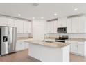 Modern kitchen featuring white cabinets, stainless steel appliances, and a large island with granite countertops at 1732 Brekey Way, Zephyrhills, FL 33541