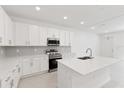 Bright, modern kitchen with white cabinets, quartz countertops, stainless steel appliances, and tile backsplash at 17330 Alderwood Ln, Punta Gorda, FL 33982