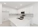 Bright, modern kitchen with white cabinets, quartz countertops, stainless steel appliances, and tile backsplash at 17330 Alderwood Ln, Punta Gorda, FL 33982
