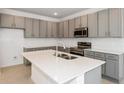 Bright kitchen featuring modern gray cabinets, stainless appliances, and a center island with sink at 17322 Alderwood Ln, Punta Gorda, FL 33982