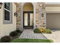 Close up of the main entryway featuring stone accents, a paved walkway, and double doors with decorative metal at 8297 Ivy Stark Blvd, Wesley Chapel, FL 33545