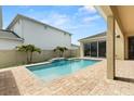 Backyard with a private in-ground swimming pool and brick paved patio plus view of the house at 8297 Ivy Stark Blvd, Wesley Chapel, FL 33545