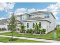 Side view of a modern two-story home with a manicured lawn and thoughtfully designed landscaping at 9201 Sanders Tree Loop, Wesley Chapel, FL 33545