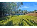 Spacious backyard with lush green grass, a wood fence, and shade trees at 5141 Mallet Dr, Port Richey, FL 34668