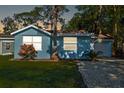 Cozy single-story home with a manicured lawn, mature trees, and a gravel driveway at 5141 Mallet Dr, Port Richey, FL 34668