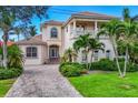 Elegant two-story home featuring a private balcony, arched windows, and a paved driveway at 811 Laguna Dr, Venice, FL 34285