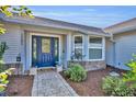 Inviting home entrance showcasing a blue front door, brick accents, and lush landscaping at 2601 Bridle Dr, Plant City, FL 33566