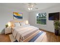 Bright bedroom with a king bed, white bedding, ceiling fan, and a view of greenery through the window at 11356 Callaway Pond Dr, Riverview, FL 33579