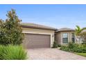 Inviting one-story home with a well-manicured lawn and a brick driveway, showcasing a modern design at 13084 Rinella St, Venice, FL 34293