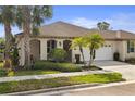 Inviting home exterior showcasing manicured landscaping, including palm trees, leading to the arched entryway and two-car garage at 11402 Peckham Pl, Tampa, FL 33625