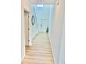 Bright hallway with wood-look flooring leads to a staircase and a white front door at 9937 Aqua Miles Path, Wesley Chapel, FL 33545