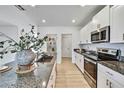 Modern kitchen featuring a granite countertop, stainless steel appliances and sleek, white cabinetry at 9937 Aqua Miles Path, Wesley Chapel, FL 33545