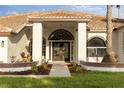 The covered entry way welcomes you to the home's gorgeous arched front doors and landscaping at 17032 Winners Cir, Odessa, FL 33556