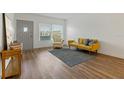 Bright living room features wood floors, gray door, modern sofa and chair, plus large windows at 2257 World Parkway W Blvd # 61, Clearwater, FL 33763