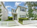 Two-story home with muted green exterior, complemented by a charming white picket fence and lush landscaping at 11314 Grand Park Ave, Riverview, FL 33578