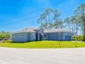 Low angle front view of a charming one-story gray house featuring a well-kept green lawn on a clear day at 14073 Naylor Ave, Port Charlotte, FL 33981