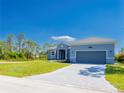 Charming single-story home with a well-manicured lawn, gray brick driveway, and an attached two-car garage at 14073 Naylor Ave, Port Charlotte, FL 33981