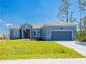 Charming single-story home with a well-manicured lawn, gray brick driveway, and an attached two-car garage at 14073 Naylor Ave, Port Charlotte, FL 33981