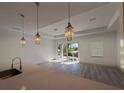 Bright living room with modern light fixtures, gray flooring, and sliding glass doors at 1495 Craleigh St, North Port, FL 34288
