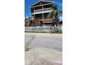 Attractive home featuring multiple decks, brown siding, a white picket fence, and mature landscaping at 19105 Whispering Pines Dr, Indian Shores, FL 33785