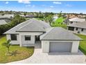An elevated view of a modern home showcasing a gray roof, attached garage, and meticulously maintained landscaping at 27 Bunker Ct, Rotonda West, FL 33947