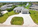 An aerial view of the house with a gray roof, attached garage, and long paved driveway in a serene neighborhood at 27 Bunker Ct, Rotonda West, FL 33947