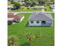 Aerial view of the back of the home with a patio surrounded by a well-maintained lawn at 3323 Elkcam Blvd, Port Charlotte, FL 33952