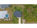 Aerial view of house with an ample backyard and surrounding lush trees and landscaping at 10071 Kingsville Dr, Port Charlotte, FL 33981