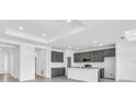 Bright, open kitchen boasts sleek gray cabinetry, a large center island, and modern stainless steel appliances at 9581 Vibrant Lane, Venice, FL 34292