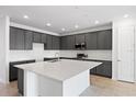 Modern kitchen featuring gray cabinets, a large white countertop island, and stainless steel appliances at 9596 Vibrant Lane, Venice, FL 34292