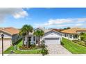 Inviting single-story home featuring a paved driveway, tropical landscaping, and an attached two-car garage at 15503 Corona Del Mar Dr, Wimauma, FL 33598