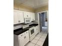 Efficient kitchen featuring white cabinets, black countertops, and tiled flooring at 4650 Orlando Cir, Bradenton, FL 34207