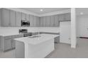 Modern kitchen with gray cabinets, stainless steel appliances, and a large center island at 17382 Alderwood Ln, Punta Gorda, FL 33982