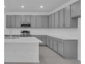 Modern kitchen with gray cabinets, stainless steel appliances, and a large center island at 17382 Alderwood Ln, Punta Gorda, FL 33982