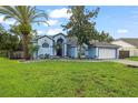 Beautiful single-story home featuring a well-manicured lawn, landscaping, a two-car garage, and a blue exterior at 28707 Raleigh Pl, Wesley Chapel, FL 33545